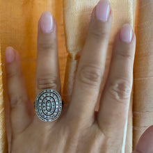 A person's hand displaying a sterling silver oval deco ring with cubic zirconia stones set in it.