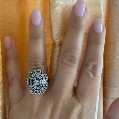 A person's hand displaying a sterling silver oval deco ring with cubic zirconia stones set in it.