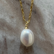 Pearl necklace with gold chain on a marble surface