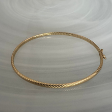 Gold bracelet on a light gray background