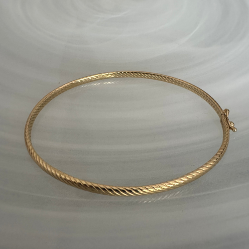 Gold bracelet on a light gray background