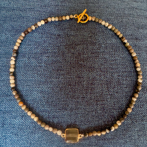 Necklace with beaded chain and gold clasp on a denim background
