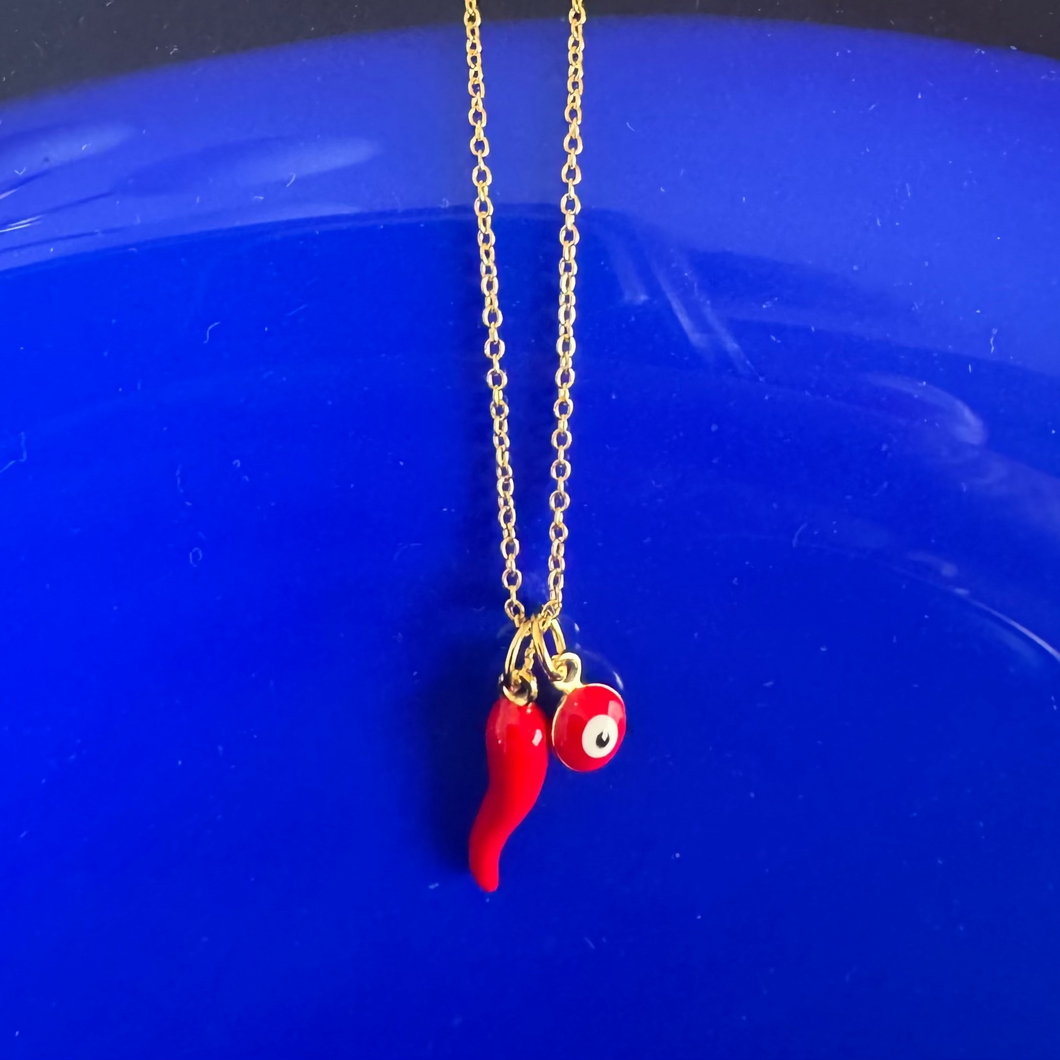Necklace with a red chili pepper and eye pendant on a blue background