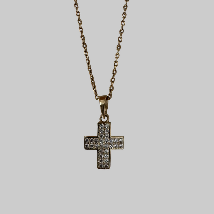 Gold necklace with a cross pendant on a light gray background