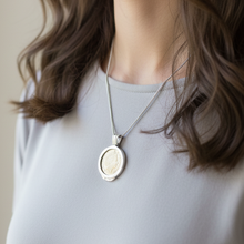 Necklace with a pendant worn by a person against a neutral background