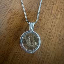 Silver necklace with a coin pendant on a wooden surface