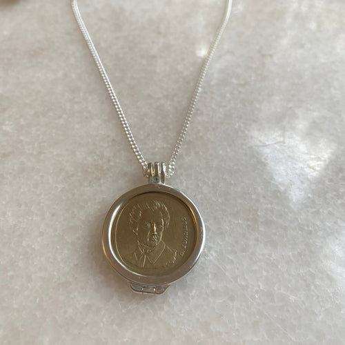 A sterling silver necklace featuring a round coin with an engraved portrait, attached to a silver curb chain with a parrot clasp.