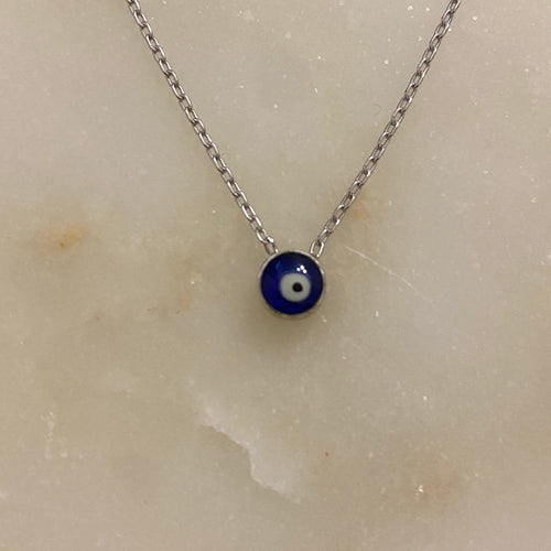 A sterling silver necklace with a yellow gold plated chain and a white and blue enamel pendant, displayed on a marble surface.
