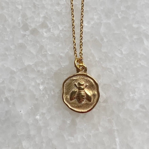 A gold-plated bee coin necklace with a sterling silver chain, displayed against a white background.