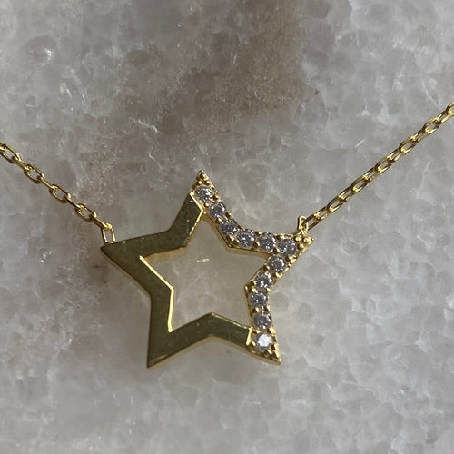 A gold-plated necklace with a star-shaped pendant featuring a chain of similar stars, displayed against a frosty background.