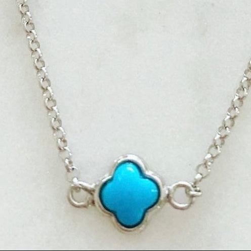 A silver necklace with a micro clover turquoise pendant on a white background